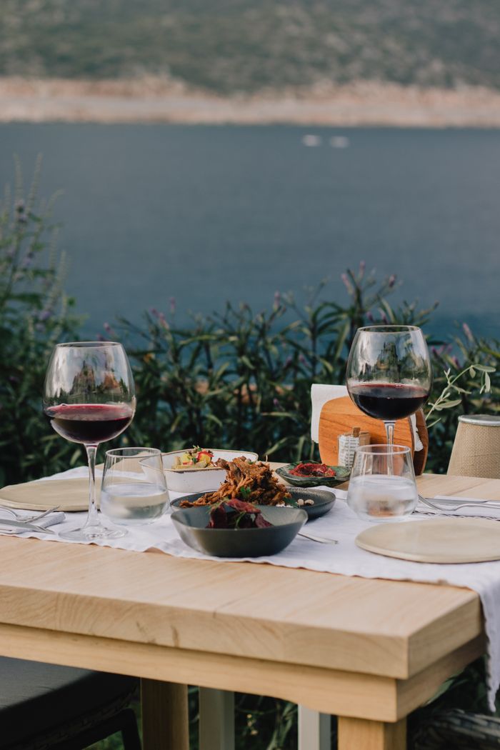 about-img A serene table setting with red wine overlooking a tranquil sea, perfect for romantic dining.